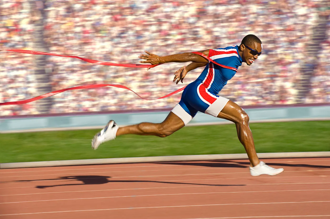 Man finishing a race running through the ribbon